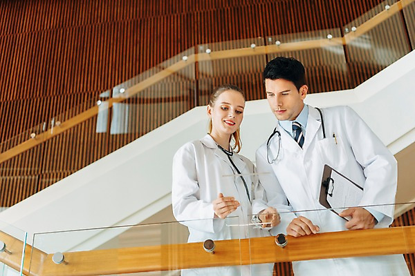 포토 JPG 서양인 응시 여자 남자 로우앵글 실내 서기 미소 들기 상반신 20대 성인 두명 앞모습 아웃포커스 계단 의사 서류판 아크릴 성인만 국내포토 외국인 시선 뷰포인트 모션 재질 촬영기법 표정 사람 청년 내부 사무용품 의료진 파일형식