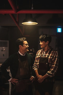 포토 JPG 남자 40대 중년 허리손 전등 실내 서기 미소 사람 상반신 20대 성인 두명 앞모습 마주보기 앞치마 한국인 작업실 고수 스승 제자 손모으기 남자만 가죽공방 국내포토 뷰포인트 포즈 모션 조명 표정 동양인 손짓 청년 내부 공예 향신료 파일형식