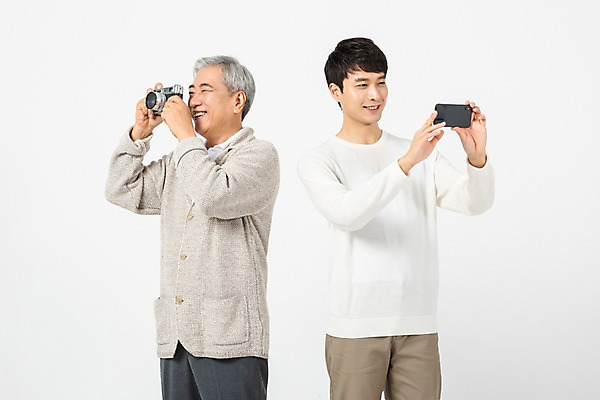 포토 JPG 스튜디오촬영 응시 노년 남자 아들 실내 미소 사람 상반신 20대 청년 두명 앞모습 옆모습 스마트폰 카메라 사진촬영 한국인 아빠 60대 흰배경 세대 소통 공감 부자지간 남자만 세대차이 국내포토 시선 뷰포인트 컨셉 가족 표정 동양인 성인 내부 전자제품 핸드폰 스마트기기 촬영 흰색 파일형식 컬러 관계 인종