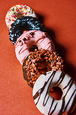 포토 JPG 스튜디오촬영 디저트 실내 종류 그림자 사람없음 도넛 달콤 일렬 토핑 빨간배경 스프링클 국내포토 음식 백그라운드 내부 장식 빨간색 맛 파일형식