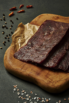 포토 JPG 스튜디오촬영 검은배경 도마 실내 사람없음 소고기 가공식품 안주 소금 기름종이 나무도마 마른안주 육포 통후추 페페론치노 국내포토 종이 백그라운드 고추 주방용품 육류 내부 목재 검은색 후추 파일형식