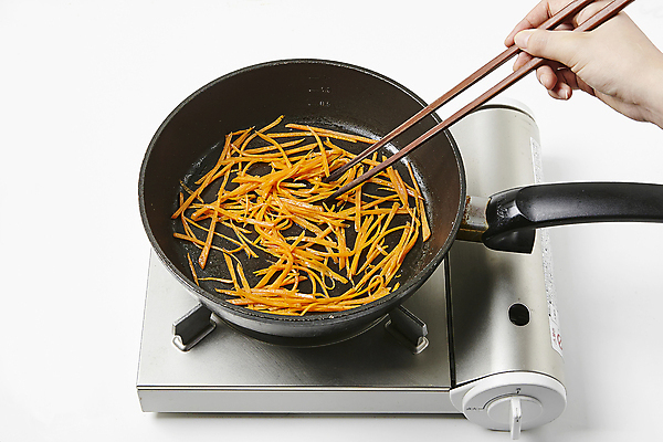 포토 JPG 손 식재료 실내 들기 신체부위 당근 프라이팬 버너 흰배경 볶음 요리중 나무젓가락 당근채 국내포토 음식 백그라운드 젓가락 모션 주방용품 뿌리채소 사람 내부 흰색 파일형식