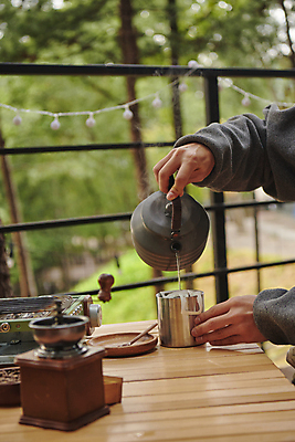 포토 JPG 주간 손 커피 여행 주전자 휴가 휴식 들기 야외 아웃포커스 신체부위 청춘 캠핑 머그컵 붓기 힐링 그라인더 나무탁자 야외테이블 핸드드립 국내포토 자연요소 음료 컨셉 모션 탁자 주방용품 레저 촬영기법 사람 컵 커피용품 파일형식