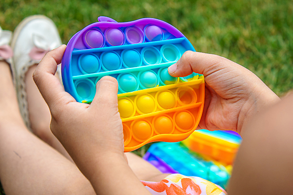 포토 JPG 해외이미지 손 어린이 휴식 잔디 신체부위 장난감 누름 즐거움 무지개색 푸시팝 해외포토 식물 감정 컨셉 모션 사람 컬러풀 파일형식