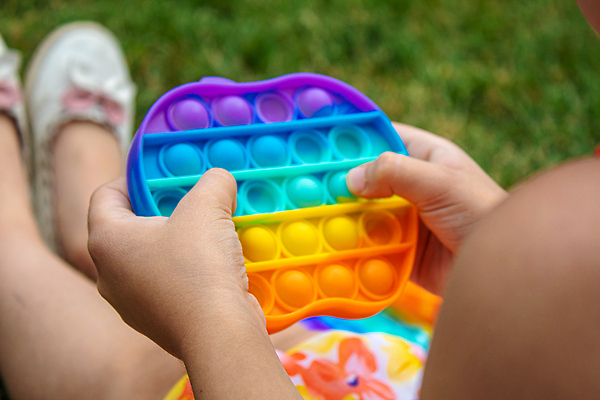 포토 JPG 해외이미지 손 어린이 휴식 잔디 신체부위 장난감 누름 즐거움 무지개색 푸시팝 해외포토 식물 감정 컨셉 모션 사람 컬러풀 파일형식