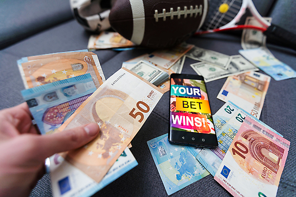 포토 JPG 해외이미지 손 돈 들기 신체부위 스마트폰 도박 어플리케이션 위험 럭비공 해외202309 해외포토 컨셉 공 모션 사람 핸드폰 스마트기기 재산 럭비용품 파일형식