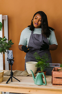 포토 JPG 해외이미지 여자 화분 흑인 한명 손짓 상반신 성인 앞모습 스마트폰 책상 원예 원예식물 삼각대 원예용품 플로리스트 성인여자한명만 인터넷방송 1인미디어 홈가드닝 해외202309 해외포토 서양인 식물 직업 1 뷰포인트 가구 생활용품 모션 사람 취미 핸드폰 스마트기기 방송 여자한명만 성인여자만 파일형식