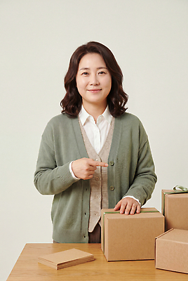 JPG 편집이미지 여자 포장 탁자 실내 선물 웃음 상자 가리킴 작업 오브젝트 의료성형뷰티 편집실사 AI인물포토 AI콘텐츠 가구 표정 사람 손짓 내부 CG 파일형식 AI포토 생활용품 모션