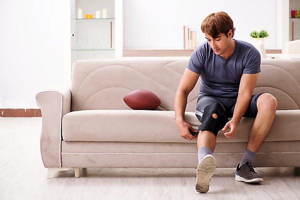 포토 JPG 해외이미지 전신 남자 실내 한명 앉기 성인 앞모습 소파 환자 잡기 럭비공 럭비선수 무릎보호대 성인남자한명만 해외202105 해외포토 1 뷰포인트 의자 공 의학 모션 운동선수 사람 내부 럭비용품 남자한명만 성인남자만 파일형식