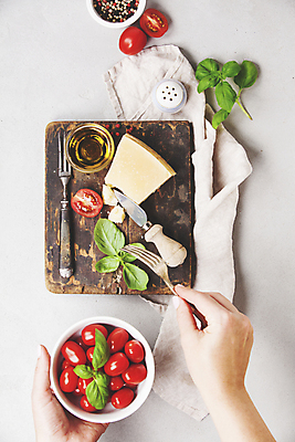 포토 JPG 해외이미지 그릇 손 포크 식재료 방울토마토 실내 들기 신체부위 올리브오일 흰배경 바질 나무도마 소금통 치즈나이프 통후추 파마산치즈 해외202004 해외포토 식기 백그라운드 토마토 모션 치즈 도마 사람 내부 목재 흰색 나이프 기름_음식 후추 파일형식