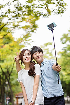 포토 JPG 주간 나무 커플 여자 남자 서기 웃음 들기 사람 동양인 손짓 상반신 20대 성인 야외 두명 앞모습 아웃포커스 사진촬영 한국인 셀프카메라 즐거움 브이 셀카봉 청년만 성인만 국내포토 자연요소 식물 감정 뷰포인트 관계 모션 촬영기법 표정 인종 청년 촬영 파일형식