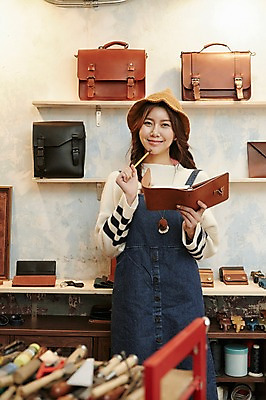 포토 JPG 모자 여자 실내 한명 서기 미소 들기 상반신 20대 성인 앞모습 연필 다이어리 전시 한국인 작업실 가죽 가죽가방 가죽공예 청년여자한명만 성인여자한명만 가죽공방 국내포토 1 잡화 뷰포인트 가방 모션 학용품 표정 사람 동양인 청년 내부 필기구 사무용품 공예 여자한명만 성인여자만 청년여자만 파일형식
