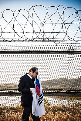 포토 JPG 주간 할아버지 노년 남자 한명 서기 정장 상반신 야외 옆모습 아웃포커스 한국인 태극기 눈물 70대 철조망 그리움 통일 노인남자한명만 임진각 실향민 국내포토 자연요소 1 옷 감정 뷰포인트 모션 촬영기법 사람 동양인 성인 국기 파주 남자한명만 노인남자만 파일형식